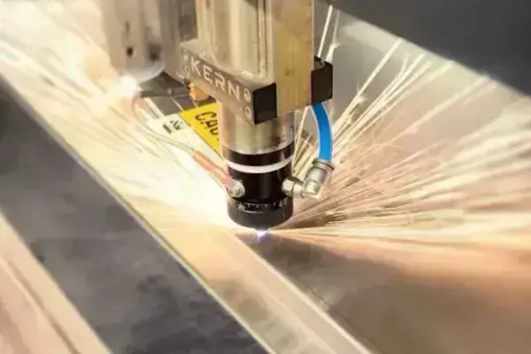 A KERN laser cutter head emits blue light and orange sparks while cutting metal.